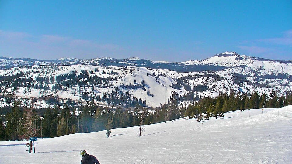 Wide winter view across Donner Ski Ranch's runs and the snowy Donner Pass ridgeline, shot from the top of Mount Judah Express at neighbouring Sugar Bowl.